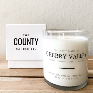 Cherry Valley hand-poured juniper, cherry blossom, and clove leaf premium soy candle in a clear glass jar made by The County Candle Co.  Hand-poured and made from 100% premium soy wax, cotton wicks, and phthalate-free fragrances infused with essential oils, we pride ourselves on creating luxurious candles using time-honored technique and eco-conscious materials. Made in Prince Edward County, Ontario, Canada. 