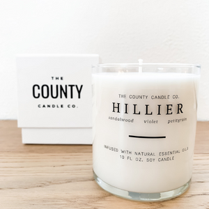 Hillier hand-poured sandalwood, violet, and petitgrain premium soy candle in a clear glass jar made by The County Candle Co.  Hand-poured and made from 100% premium soy wax, cotton wicks, and phthalate-free fragrances infused with essential oils, we pride ourselves on creating luxurious candles using time-honored technique and eco-conscious materials. Made in Prince Edward County, Ontario, Canada. 