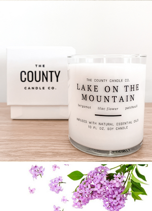 Open image in slideshow, Lake on the Mountain hand-poured bergamot, lilac flower, and patchouli premium soy candle in a clear glass jar made by The County Candle Co.  Hand-poured and made from 100% premium soy wax, cotton wicks, and phthalate-free fragrances infused with essential oils, we pride ourselves on creating luxurious candles using time-honored technique and eco-conscious materials. Made in Prince Edward County, Ontario, Canada. 
