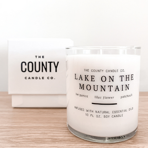 Lake on the Mountain hand-poured bergamot, lilac flower, and patchouli premium soy candle in a clear glass jar made by The County Candle Co.  Hand-poured and made from 100% premium soy wax, cotton wicks, and phthalate-free fragrances infused with essential oils, we pride ourselves on creating luxurious candles using time-honored technique and eco-conscious materials. Made in Prince Edward County, Ontario, Canada. 