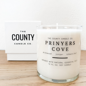 Prinyers Cove hand-poured driftwood, juniper, and tobacco leaf premium soy candle in a clear glass jar, made by The County Candle Co.  Hand-poured and made from 100% premium soy wax, cotton wicks, and phthalate-free fragrances infused with essential oils, we pride ourselves on creating luxurious candles using time-honored technique and eco-conscious materials. Made in Prince Edward County, Ontario, Canada. 