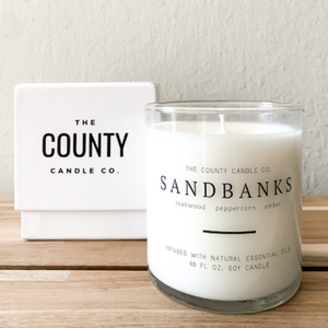 Sandbanks hand-poured teakwood, peppercorn, amber premium soy candle in a clear glass jar made by The County Candle Co.  Hand-poured and made from 100% premium soy wax, cotton wicks, and phthalate-free fragrances infused with essential oils, we pride ourselves on creating luxurious candles using time-honored technique and eco-conscious materials. Made in Prince Edward County, Ontario, Canada. 